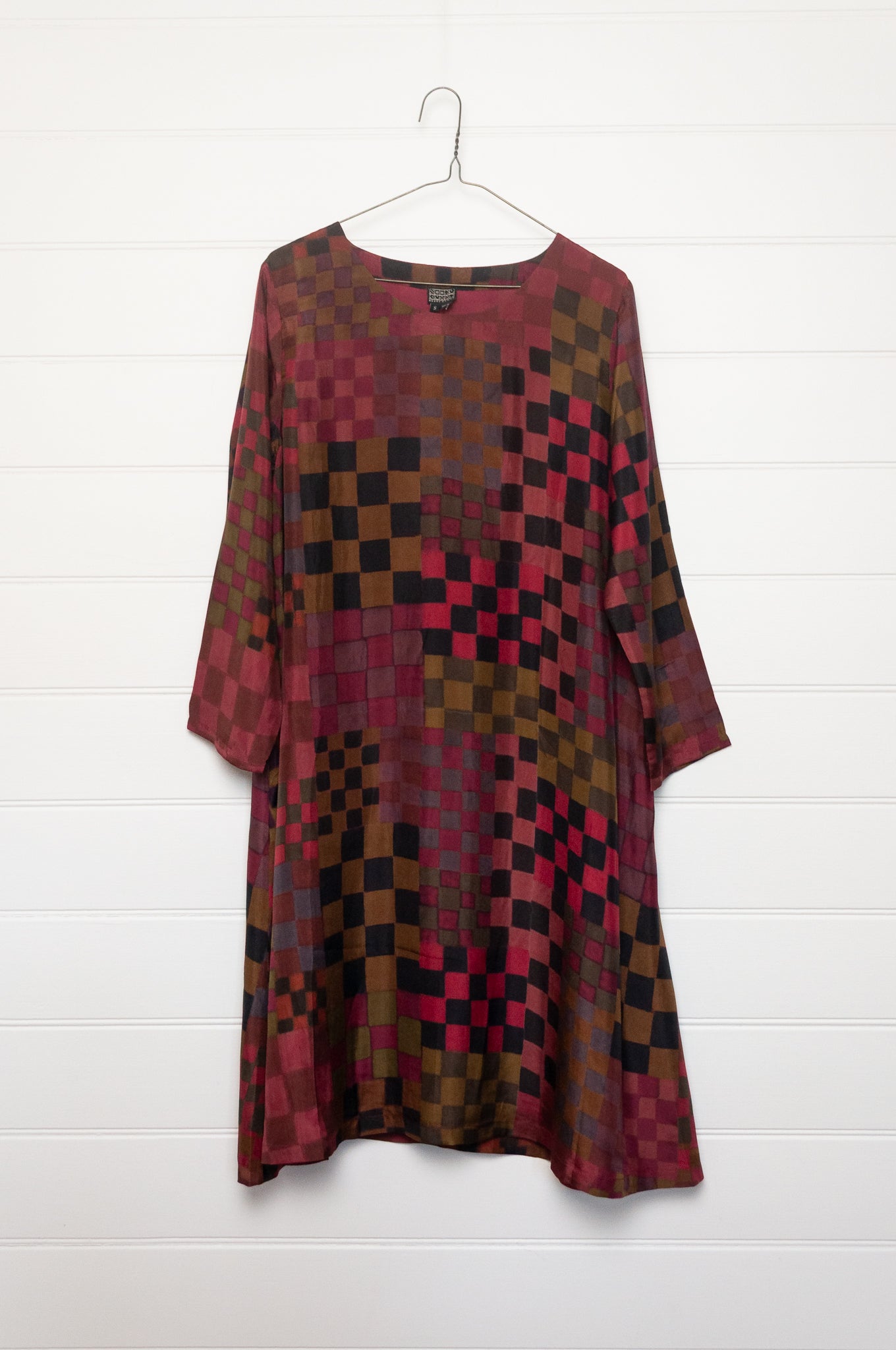Neeru Kumar pure silk digital print A-line long-sleeved tunic dress with a geometric checkerboard pattern in shades of burgundy, magenta, brown, and black.