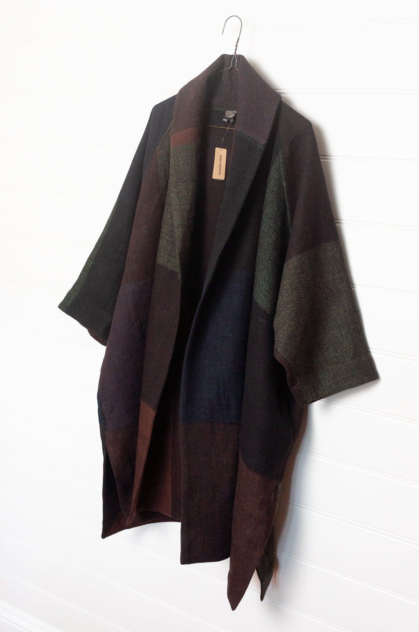 Neeru Kumar handwoven wool cape cardigan jacket coat in multicolor block pattern of charcoal, brown, aubergine purple, and black.