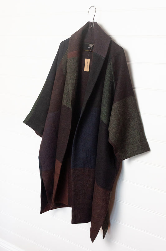 Neeru Kumar handwoven wool cape cardigan jacket coat in multicolor block pattern of charcoal, brown, aubergine purple, and black.