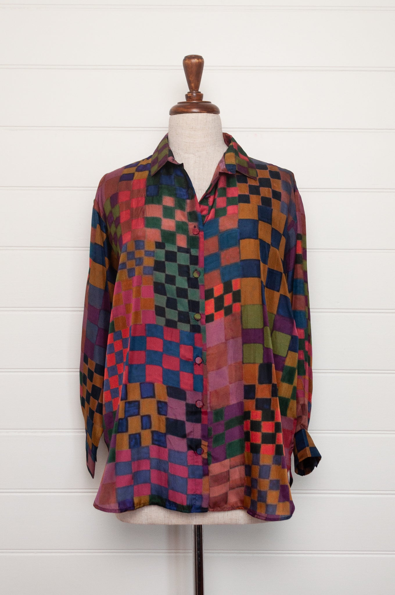 Neeru Kumar pure silk digital print button up long-sleeved blouse with a geometric checkerboard pattern in shades of burgundy, magenta, olive, blue, brown, and black.