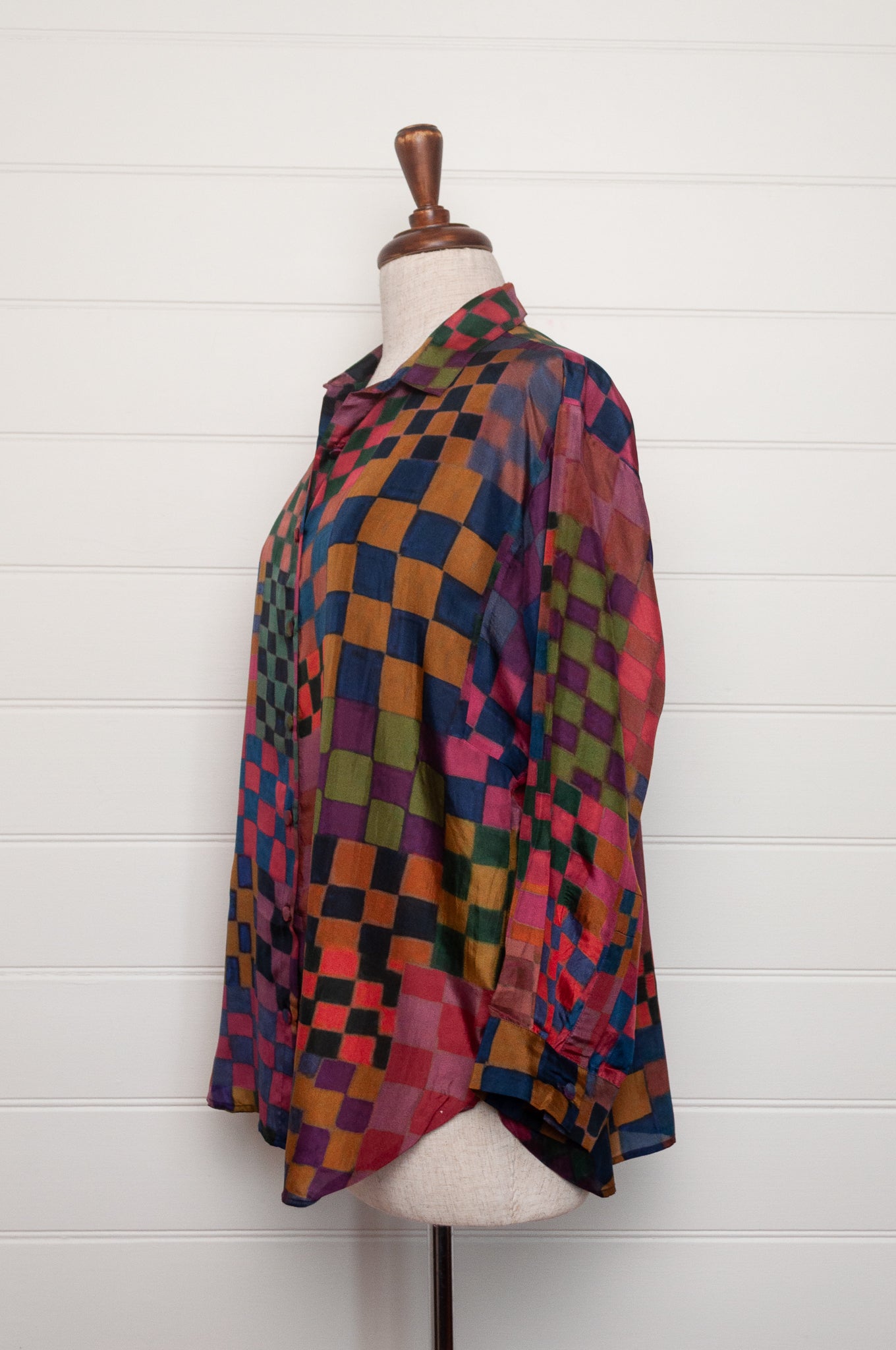 Neeru Kumar pure silk digital print button up long-sleeved blouse with a geometric checkerboard pattern in shades of burgundy, magenta, olive, blue, brown, and black.