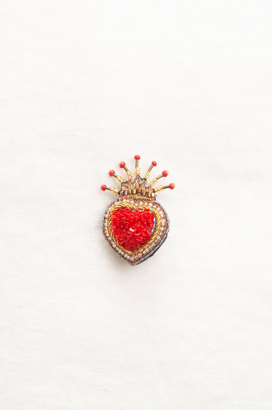 Trovelore Queen of Hearts hand beadedheart-shaped brooch featuring a vibrant red central heart, surrounded by a gold and silver beaded border, topped with a small gold crown adorned with red beads.