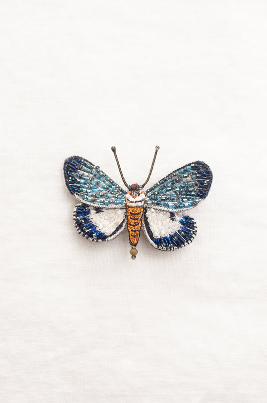 Trovelore Neochera moth hand beaded brooch, detailed butterfly-shaped brooch with iridescent blue and white wings, a metallic gold body, and delicate antennae.