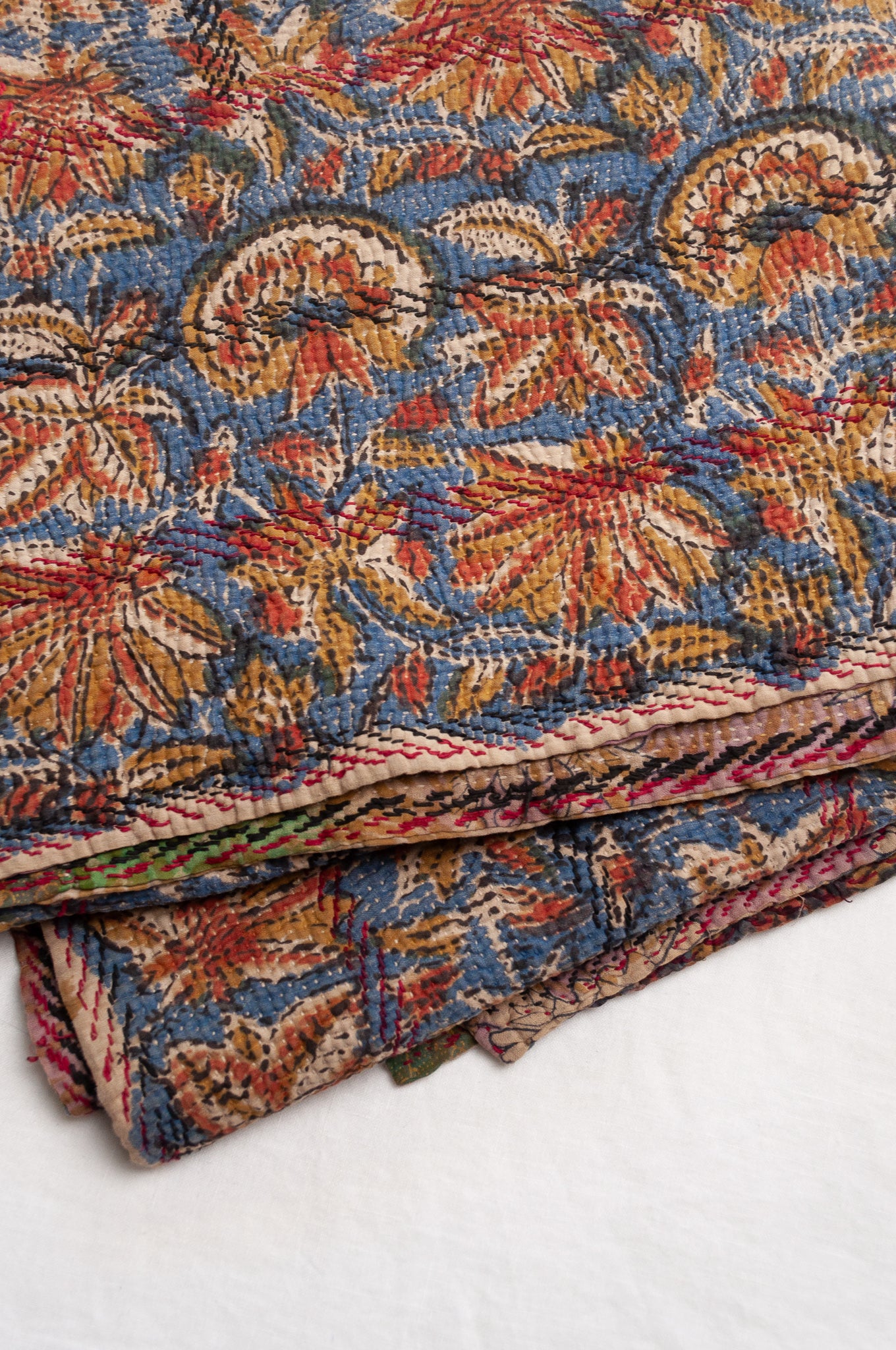 Vintage kantha quilt Bagru blockprinted in indigo, mustard and rust brown, floral design with red and dark green embroidery.