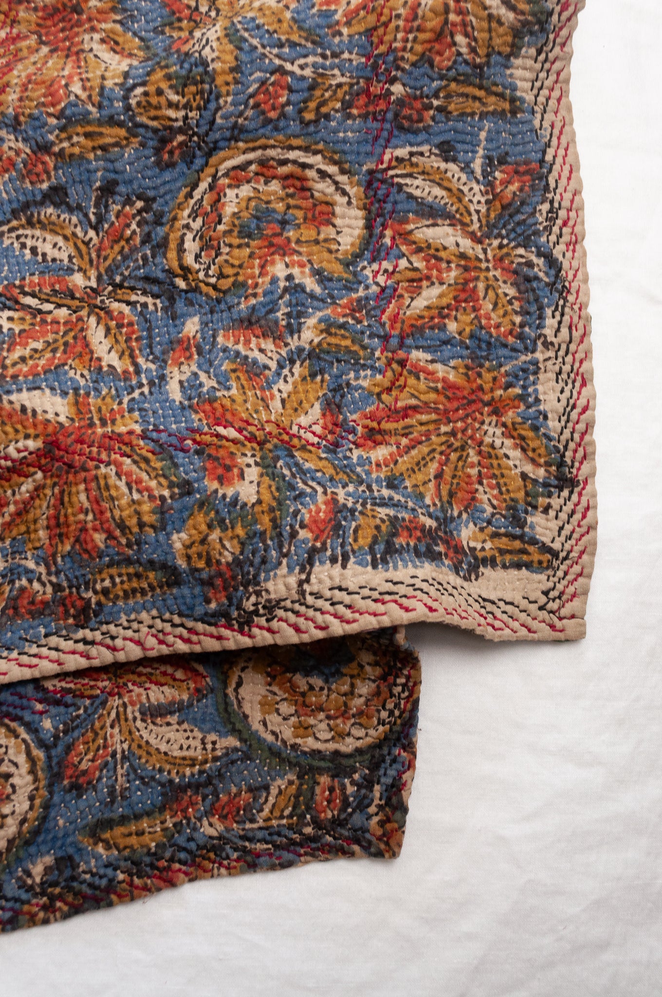 Vintage kantha quilt Bagru blockprinted in indigo, mustard and rust brown, floral design with red and dark green embroidery.