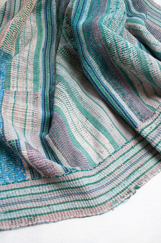 Striped kantha quilt, with checks and patches in greens and blues with highlights of pink.