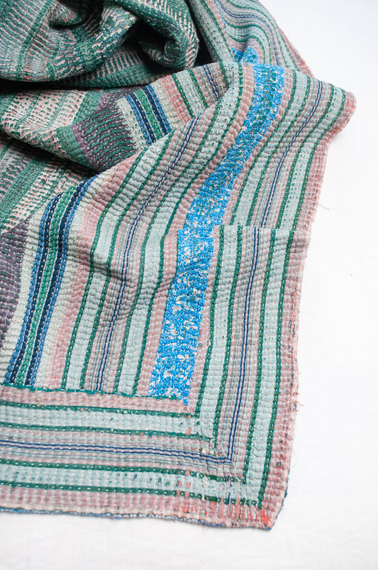 Striped kantha quilt, with checks and patches in greens and blues with highlights of pink.