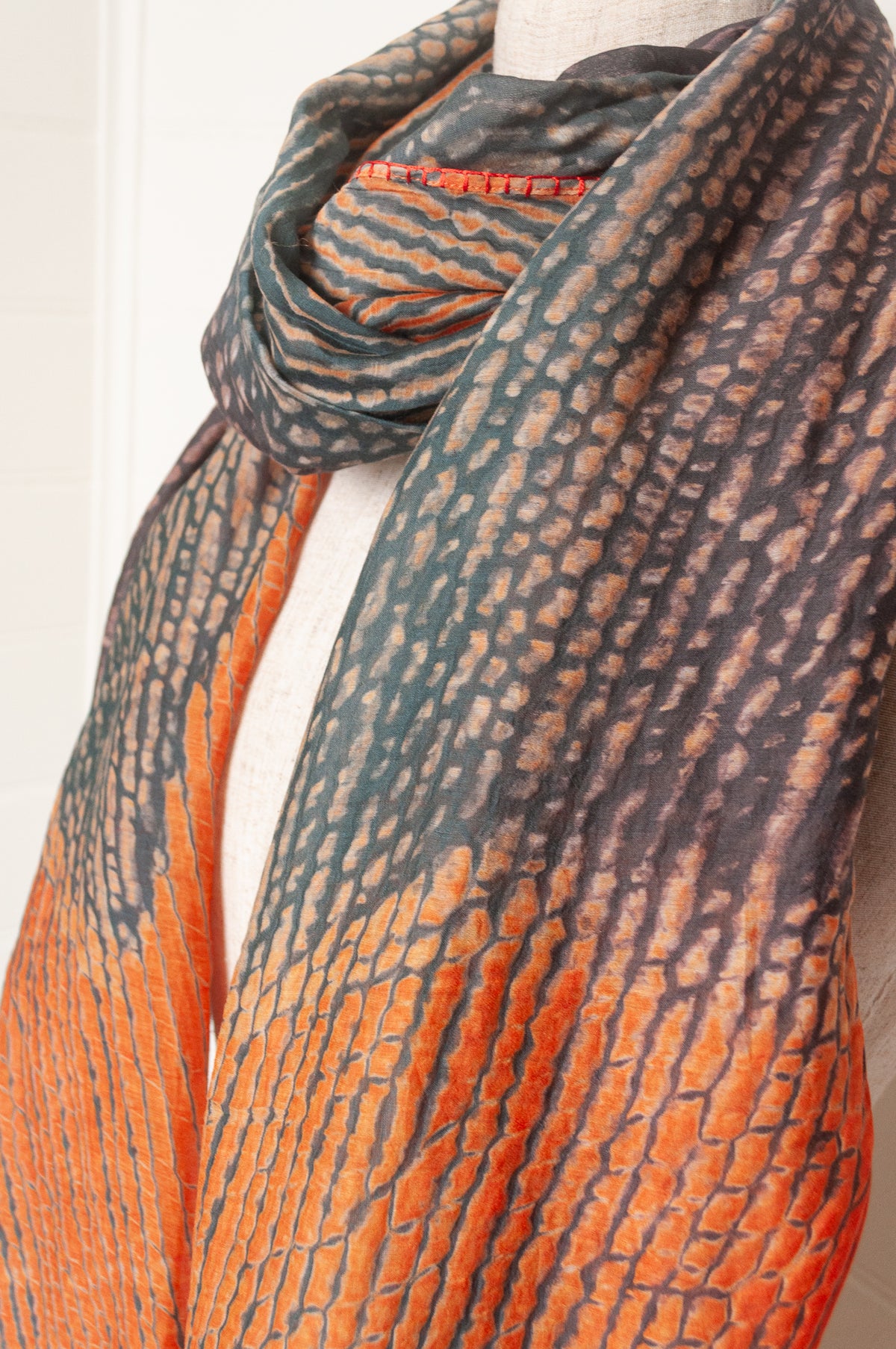 Neeru Kumar shibori dyed cotton silk scarf in charcoal and orange, with handstitched edgings and tiny tassels in red.