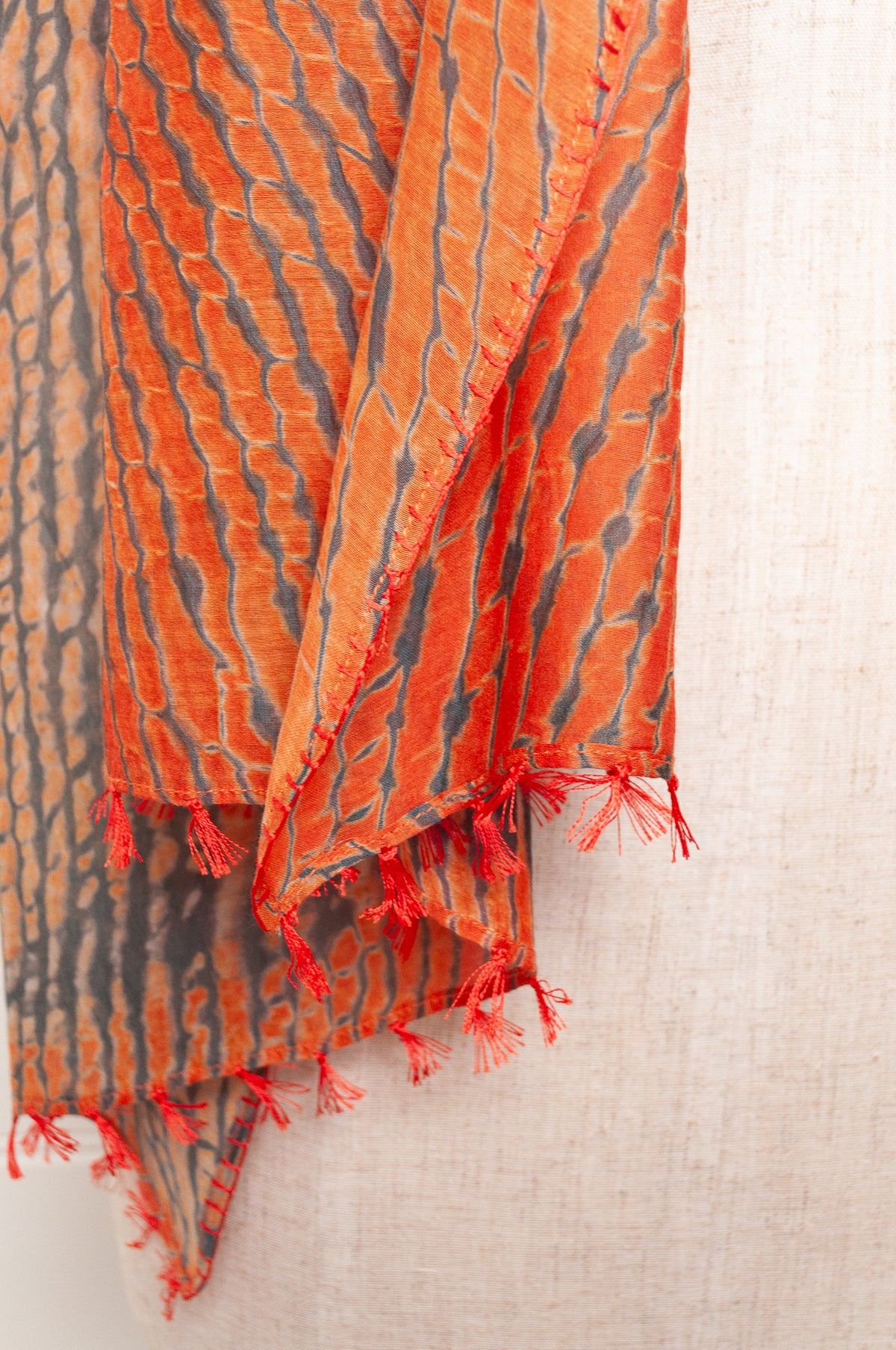 Neeru Kumar shibori dyed cotton silk scarf in charcoal and orange, with handstitched edgings and tiny tassels in red.