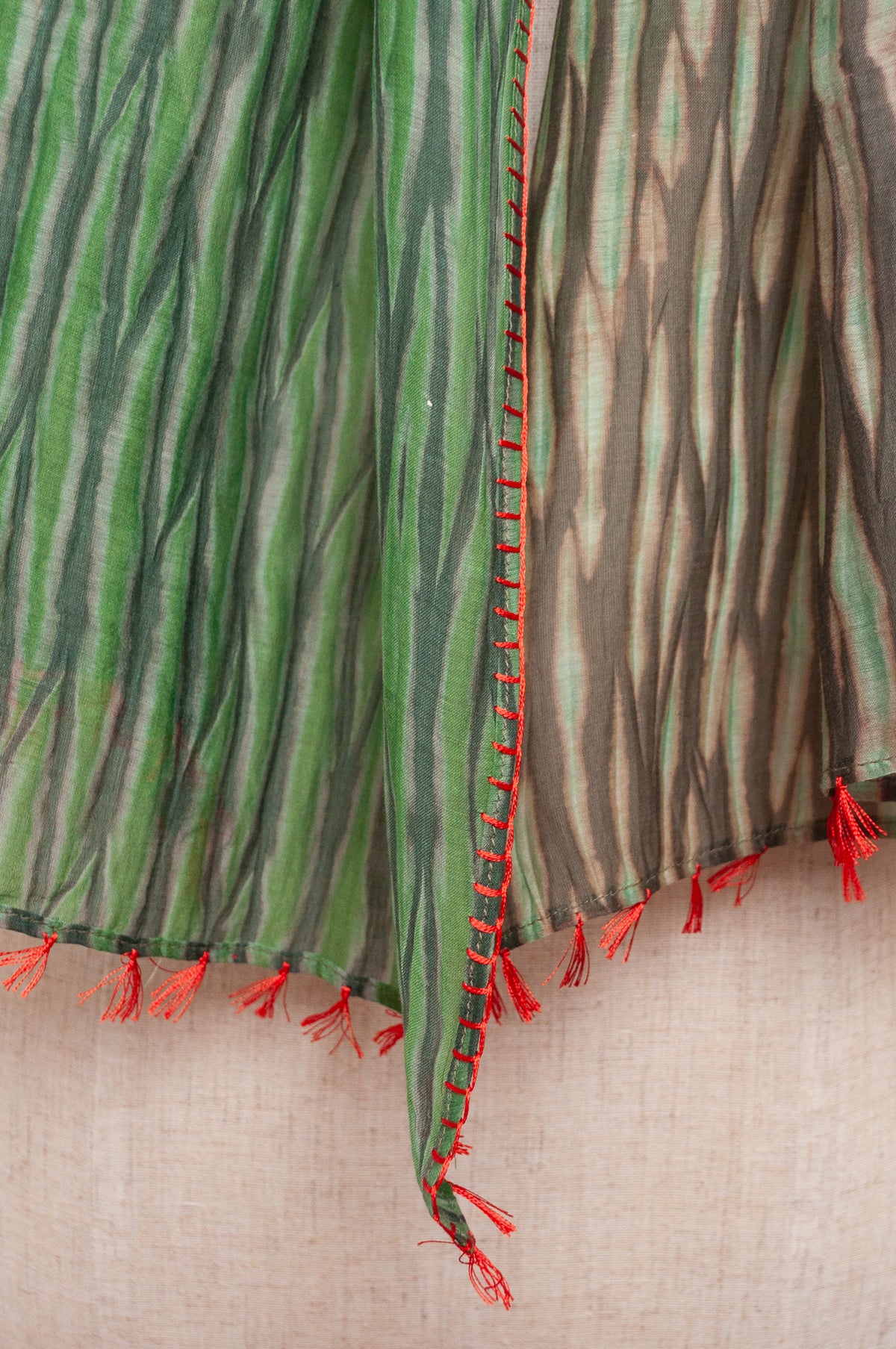 Neeru Kumar shibori dyed cotton silk scarf in shades of green, with handstitched edgings and tiny tassels in red.