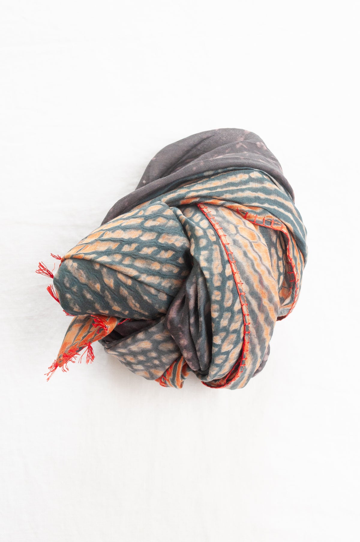 Neeru Kumar shibori dyed cotton silk scarf in charcoal and orange, with handstitched edgings and tiny tassels in red.