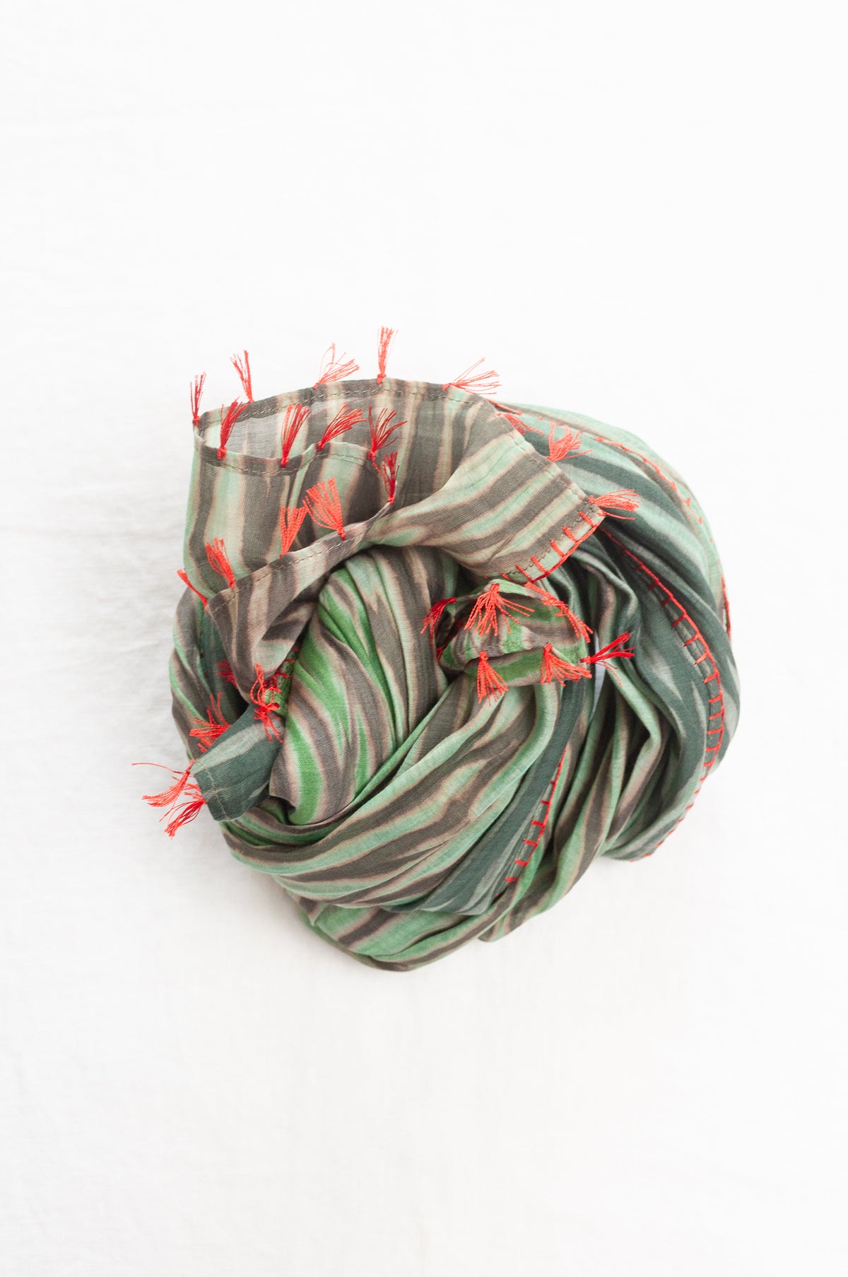 Neeru Kumar shibori dyed cotton silk scarf in shades of green, with handstitched edgings and tiny tassels in red.