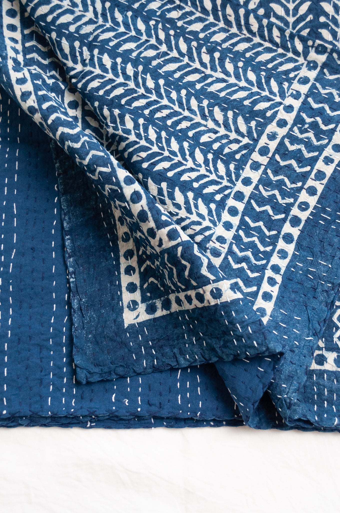 Pure cotton indigo kantha quilt hand stitched with vertical vine design and patterned border.