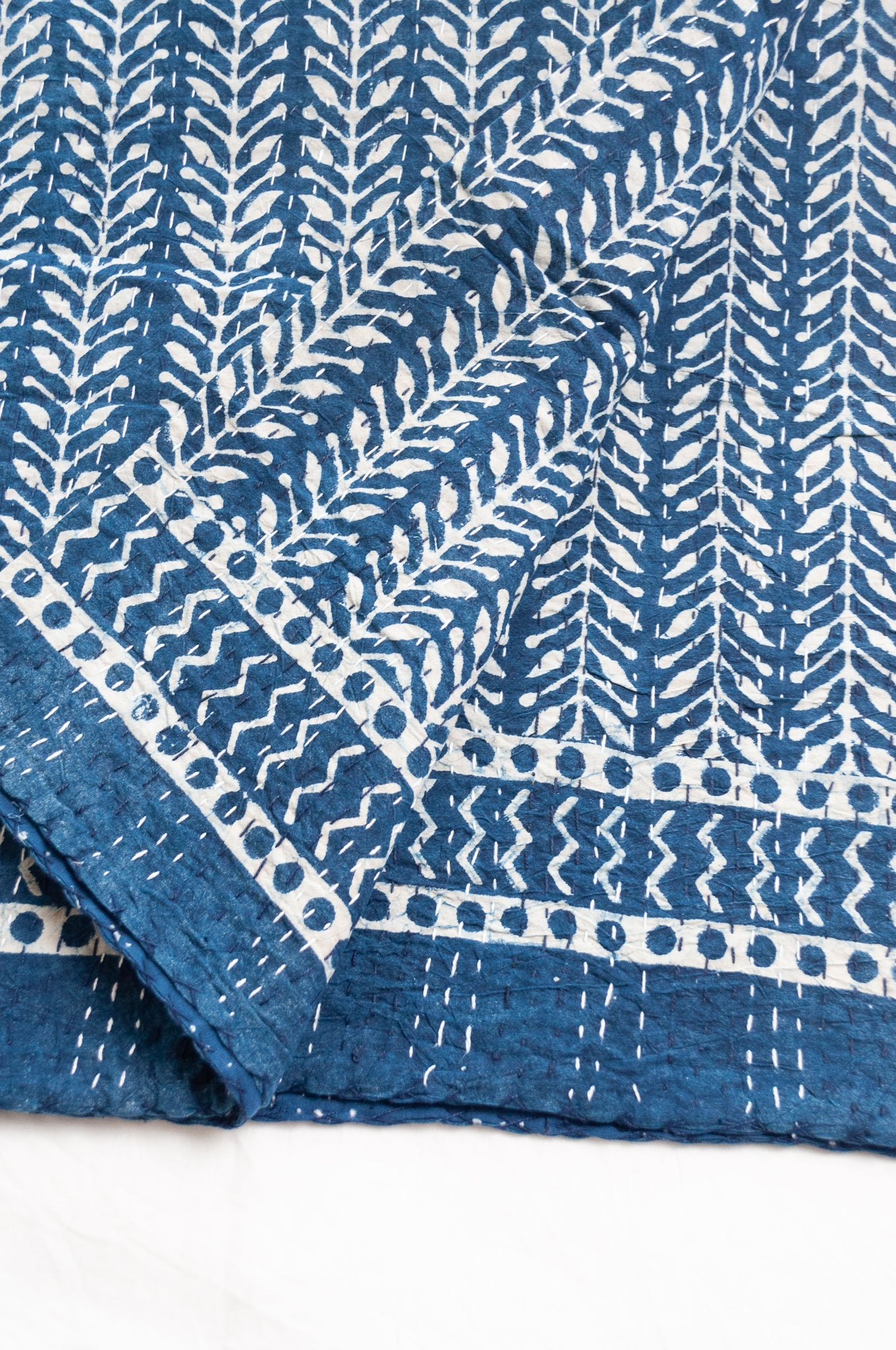 Pure cotton indigo kantha quilt hand stitched with vertical vine design and patterned border.