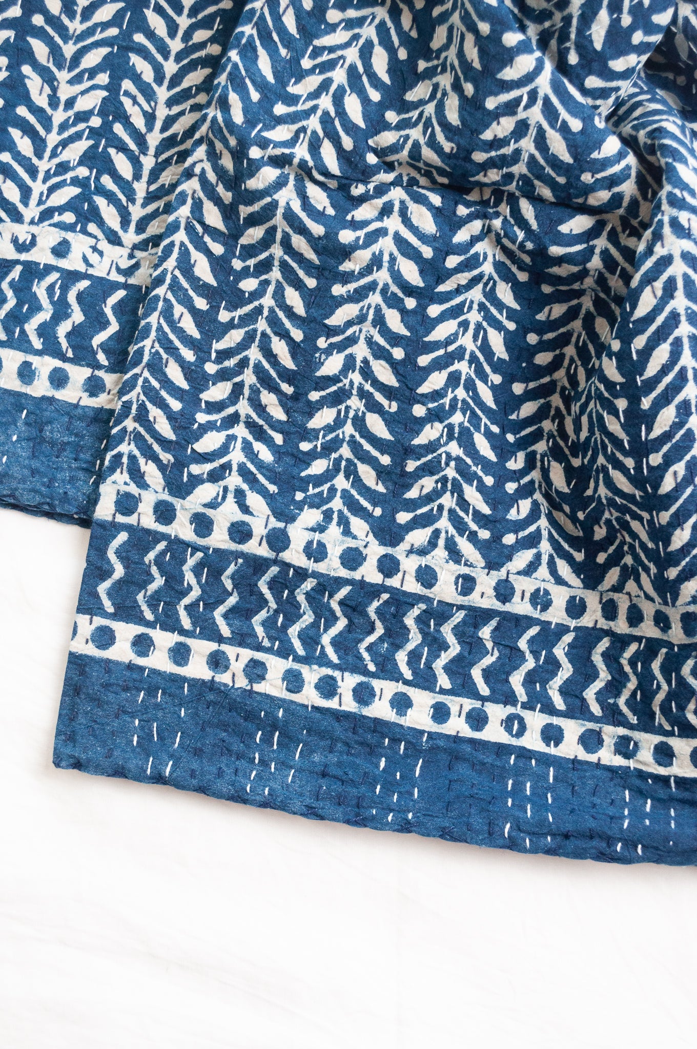 Pure cotton indigo kantha quilt hand stitched with vertical vine design and patterned border.
