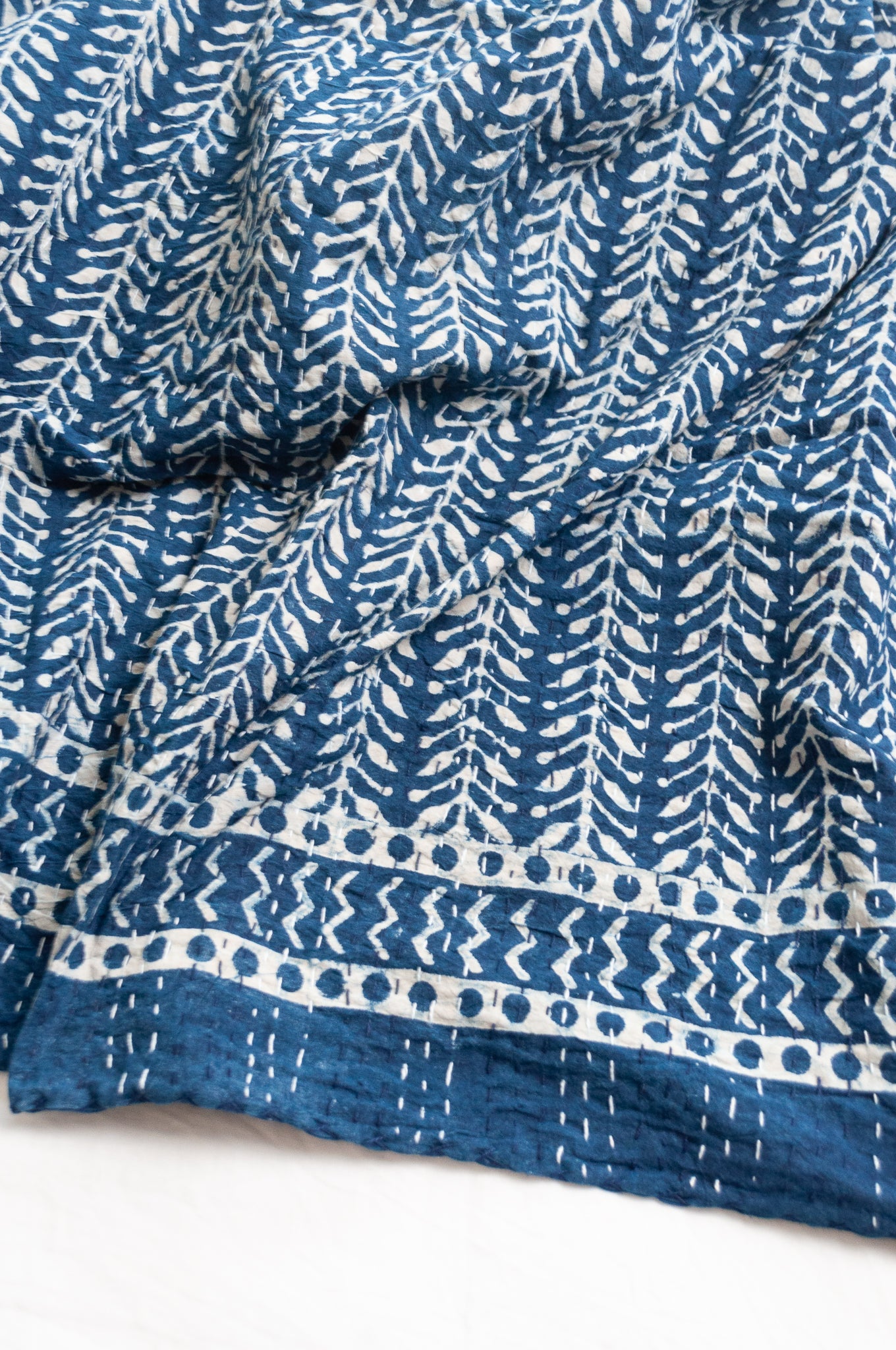 Pure cotton indigo kantha quilt hand stitched with vertical vine design and patterned border.