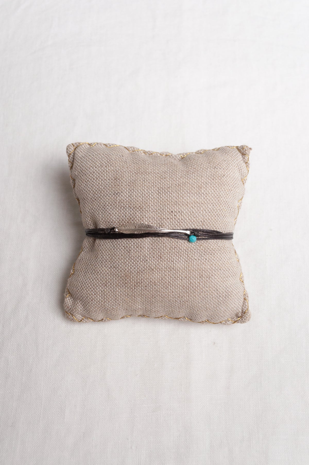 Mary Gaitani hand tooled silver feather bracelet on charcoal waxed cord with turquoise bead.