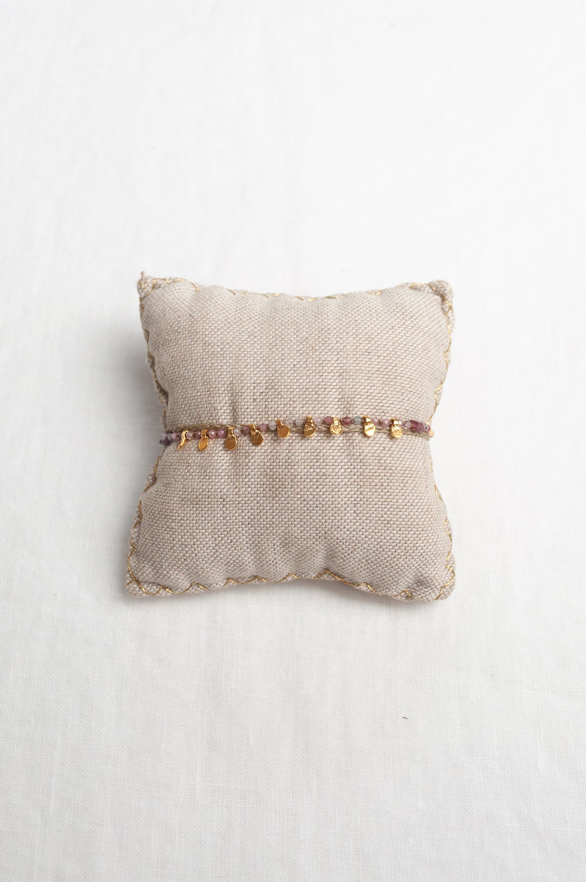 Mary Gaitani hand tooled gold charms on taupe waxed plaited cord with semi-precious stones.