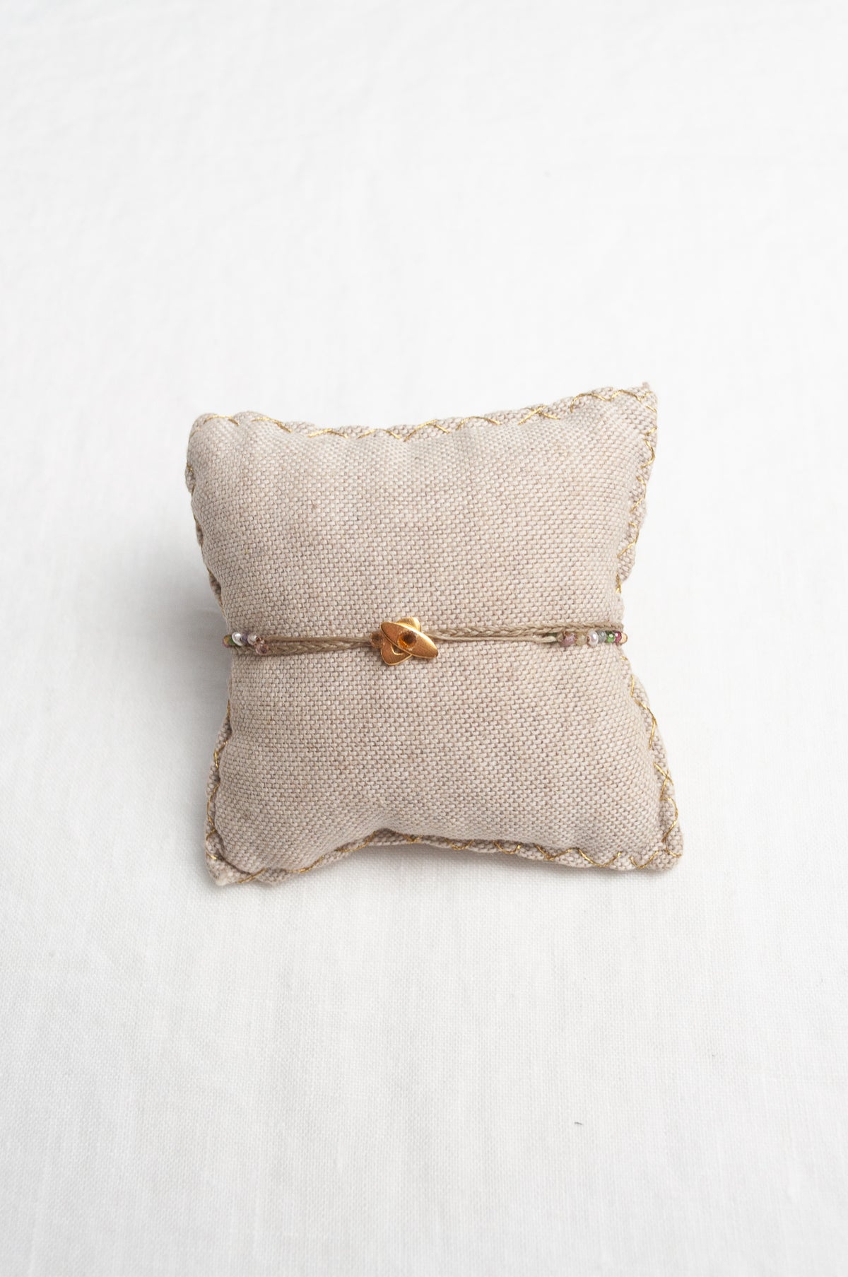 Mary Gaitani hand tooled gold charms on taupe waxed plaited cord with semi-precious stones.