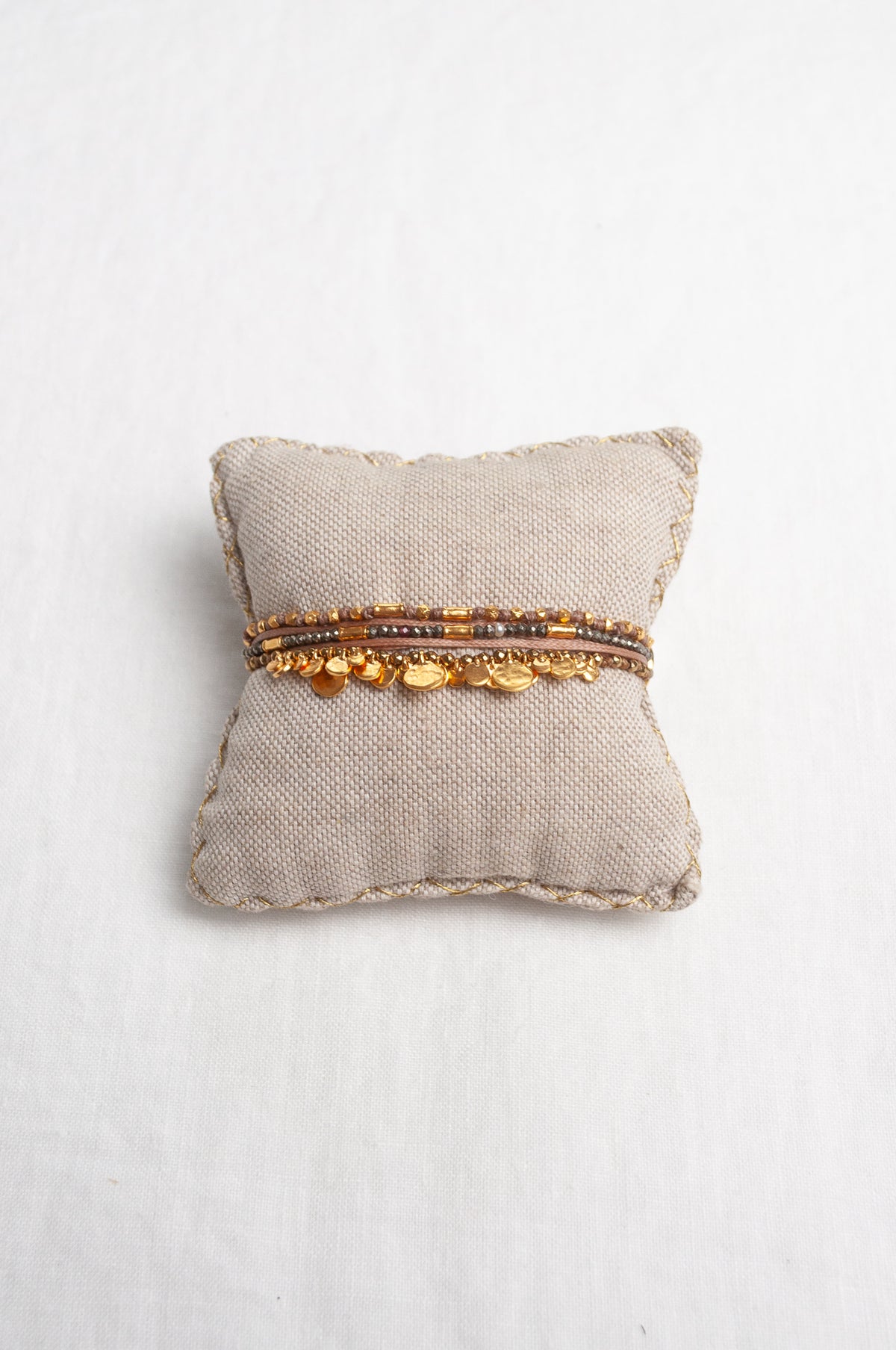 Mary Gaitani hand tooled gold charms on stranded taupe cords with semi-precious stones.