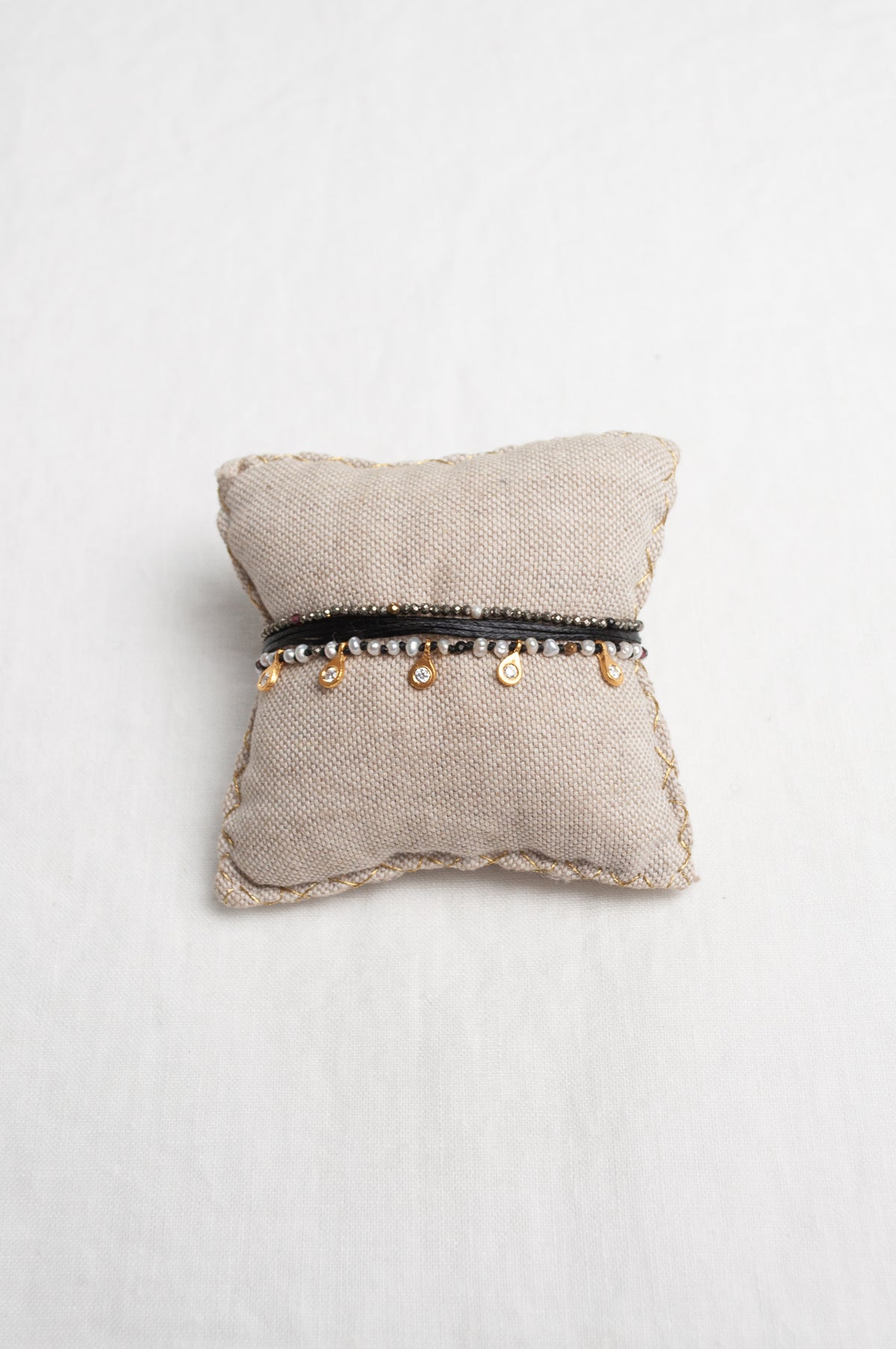 Mary Gaitani hand tooled gold charms on stranded cords with zircons and seed pearls.
