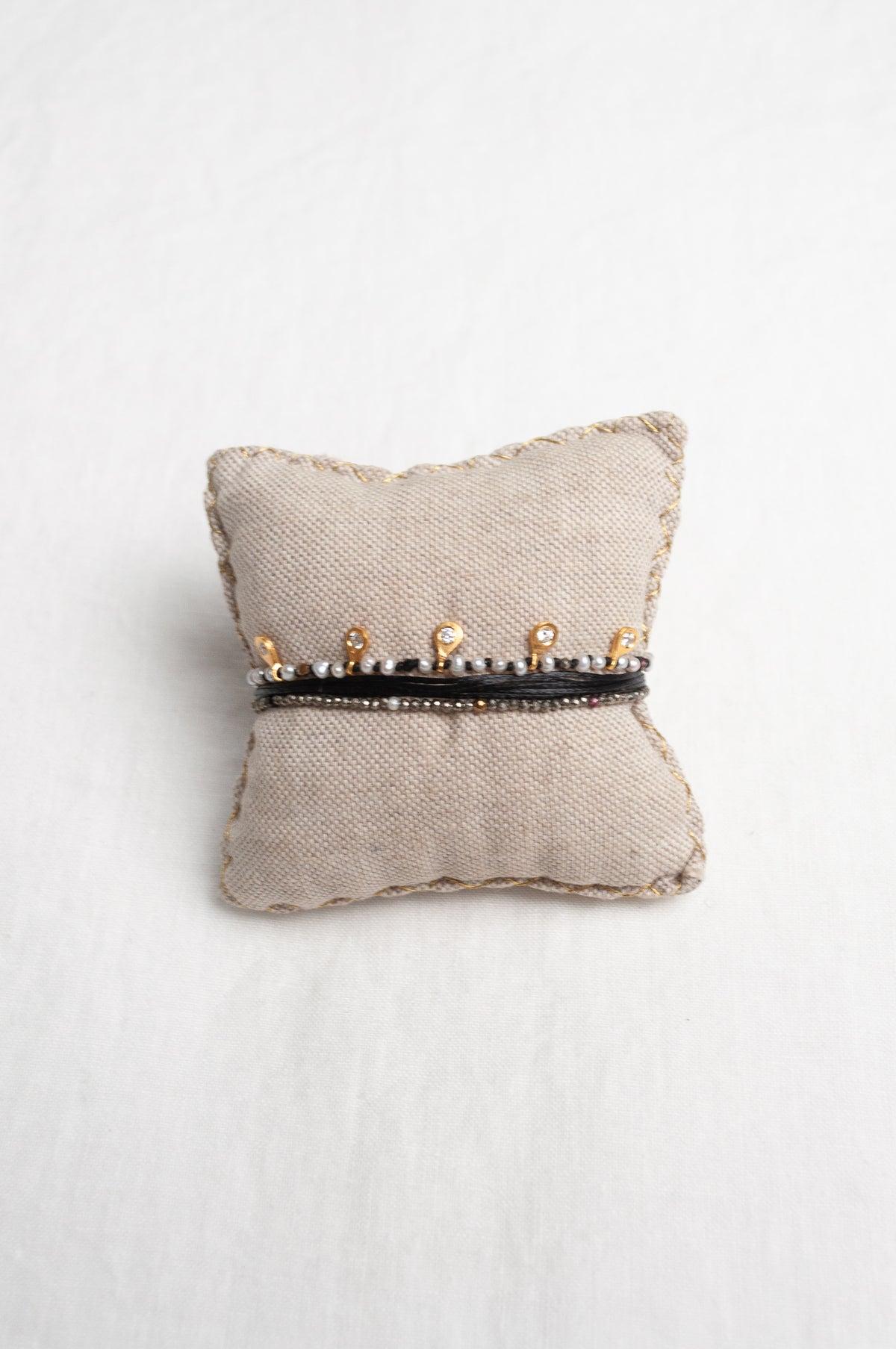 Mary Gaitani hand tooled gold charms on stranded cords with zircons and seed pearls.