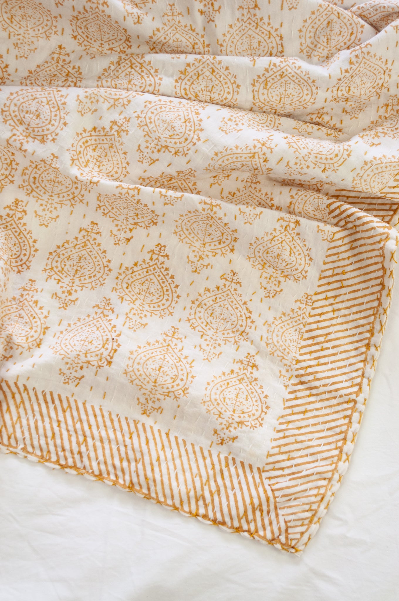 Mustard yellow on white Mughal motif blockprint kantha quilt.