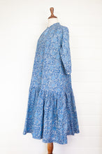Load image into Gallery viewer, Juniper Hearth Gina dress in blue grey floral blockprint, loose fit three quarter sleeve with ruffle skirt.