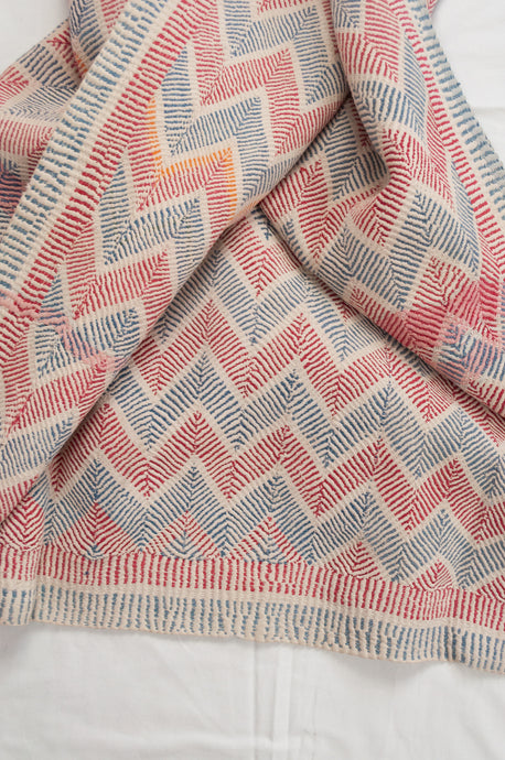 Traditional lohori wave kantha quilt red and blue stitching on white background.