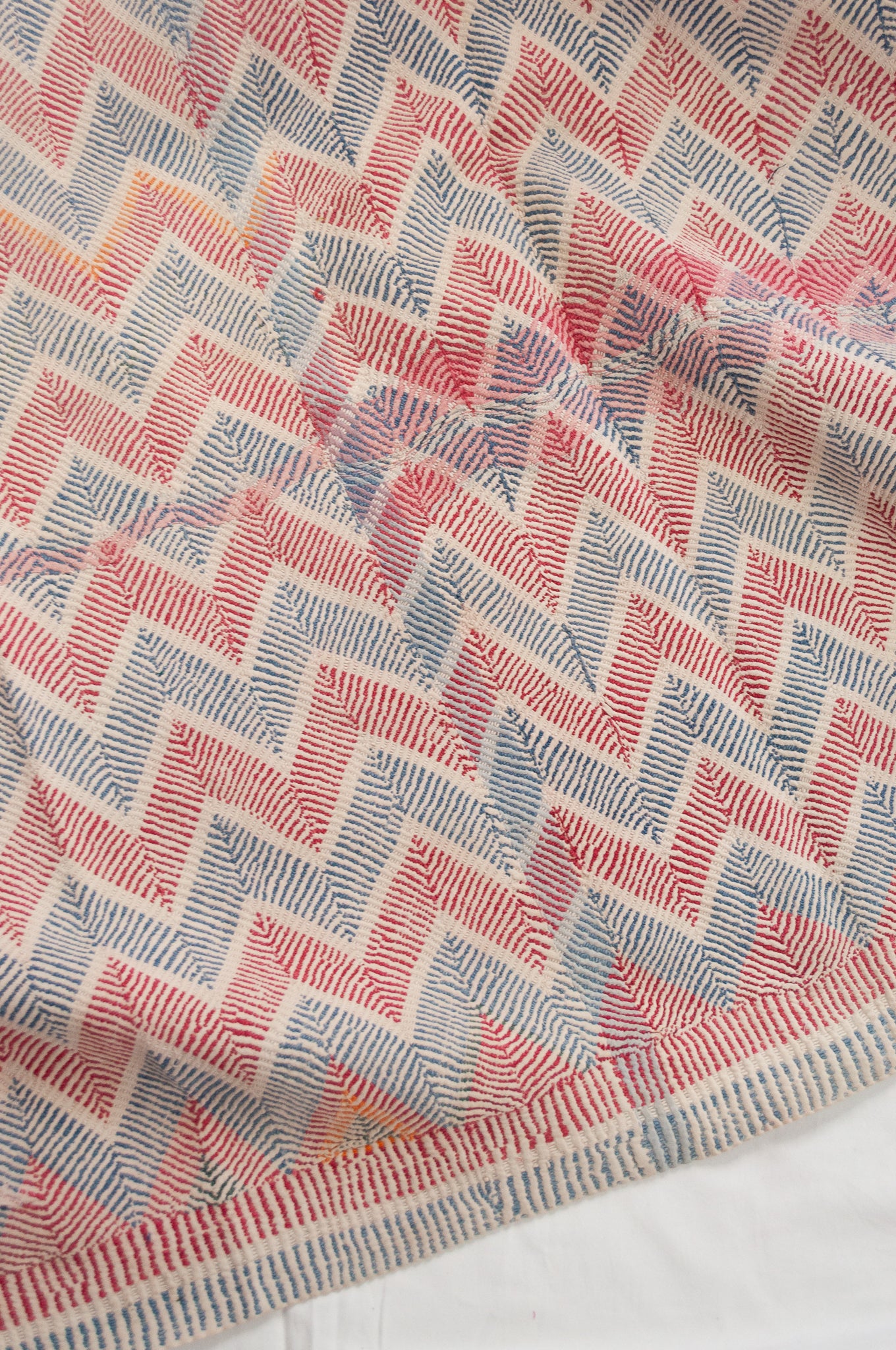 Traditional lohori wave kantha quilt red and blue stitching on white background.