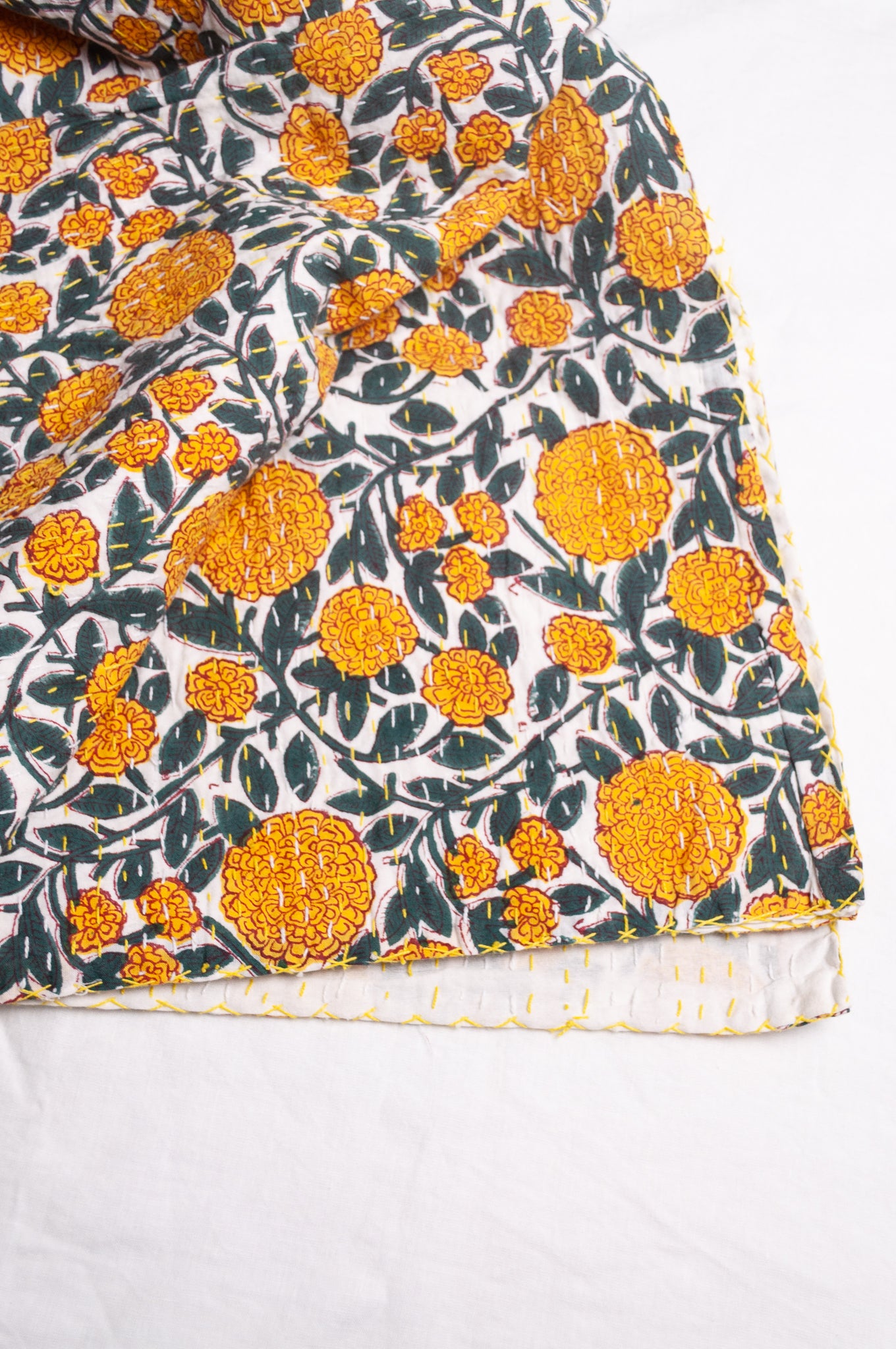 Hand stitched block print pure cotton kantha quilt marigold yellow and dark green floral on white.
