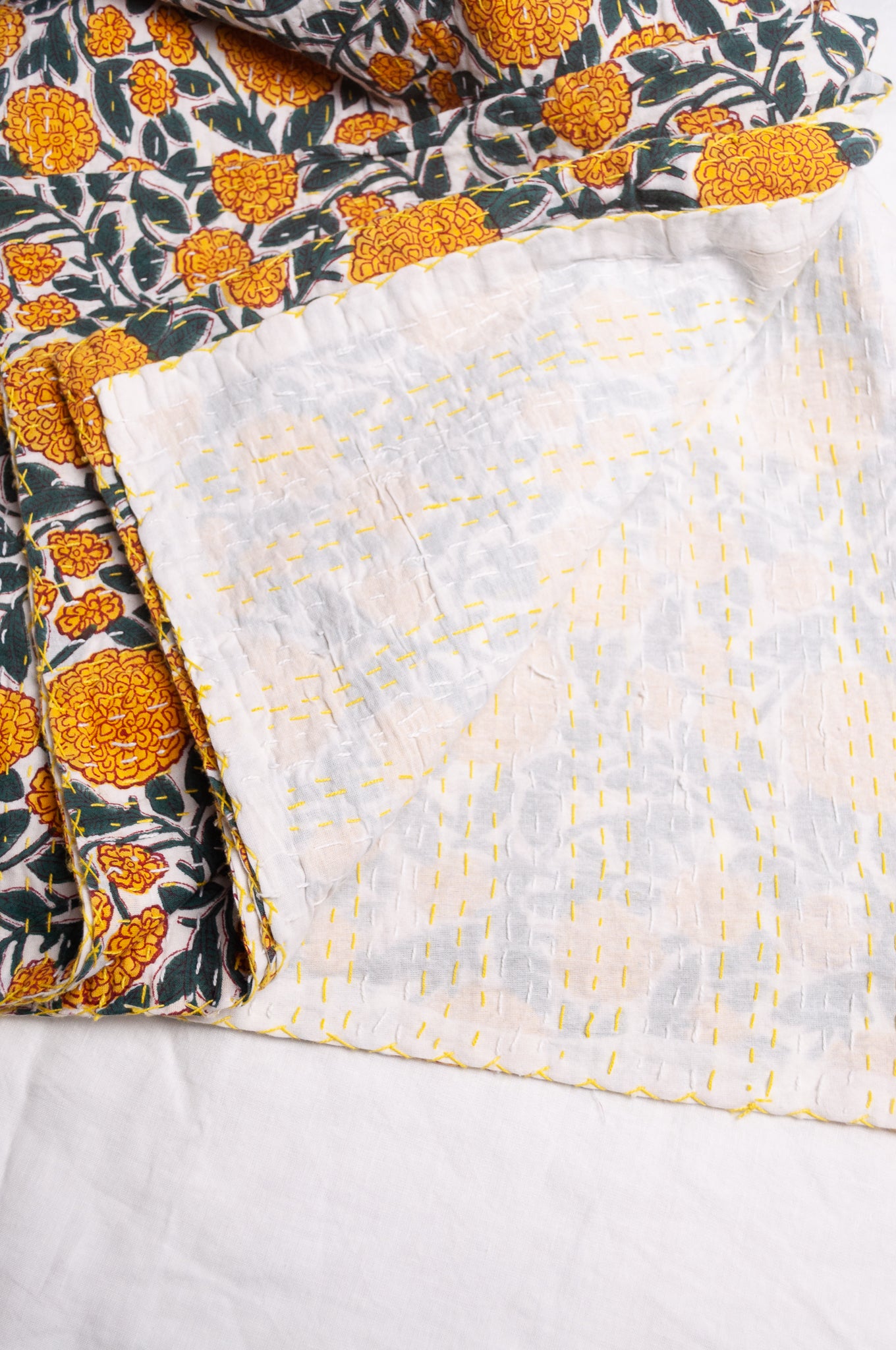 Hand stitched block print pure cotton kantha quilt marigold yellow and dark green floral on white.