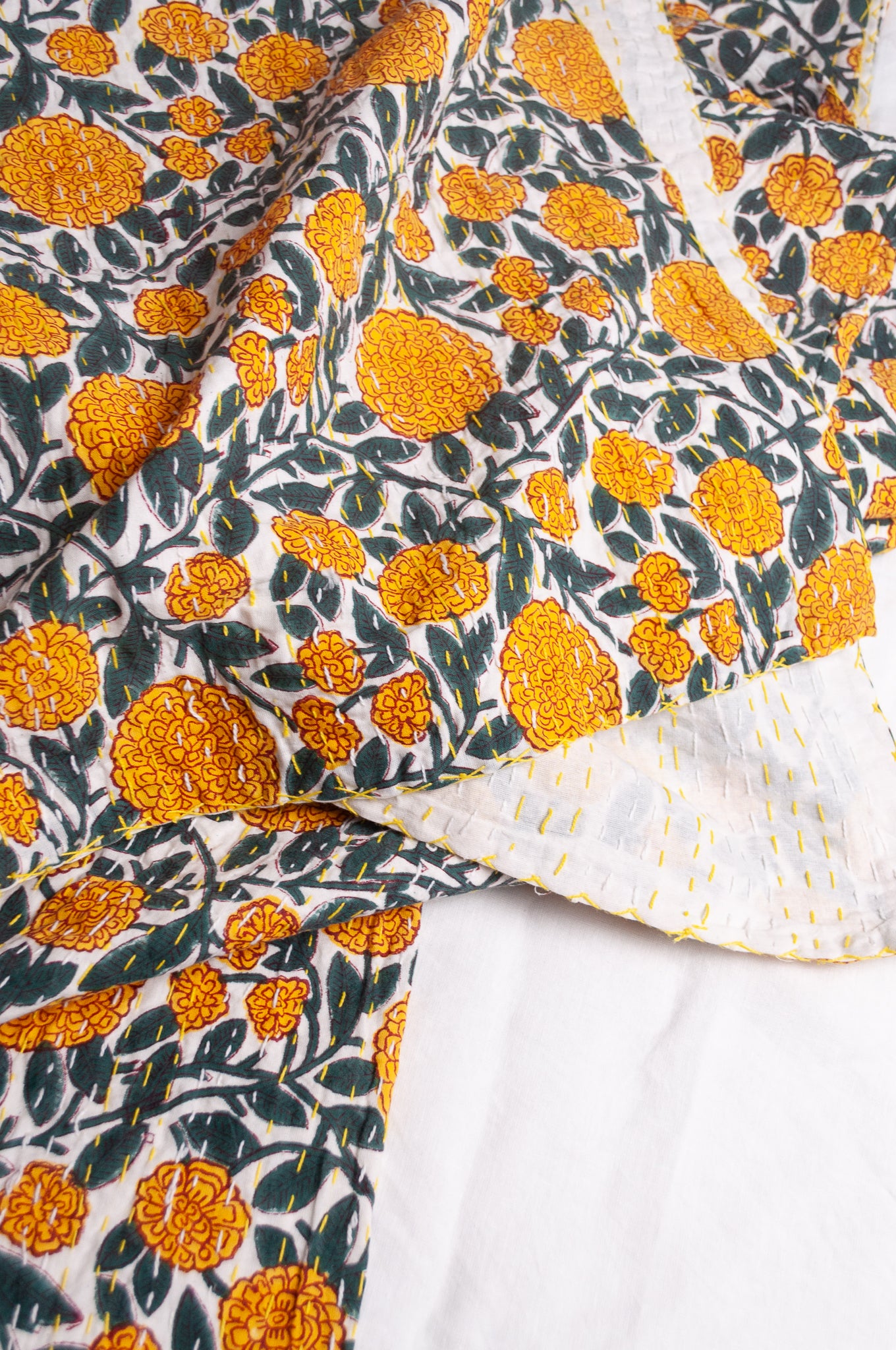 Hand stitched block print pure cotton kantha quilt marigold yellow and dark green floral on white.
