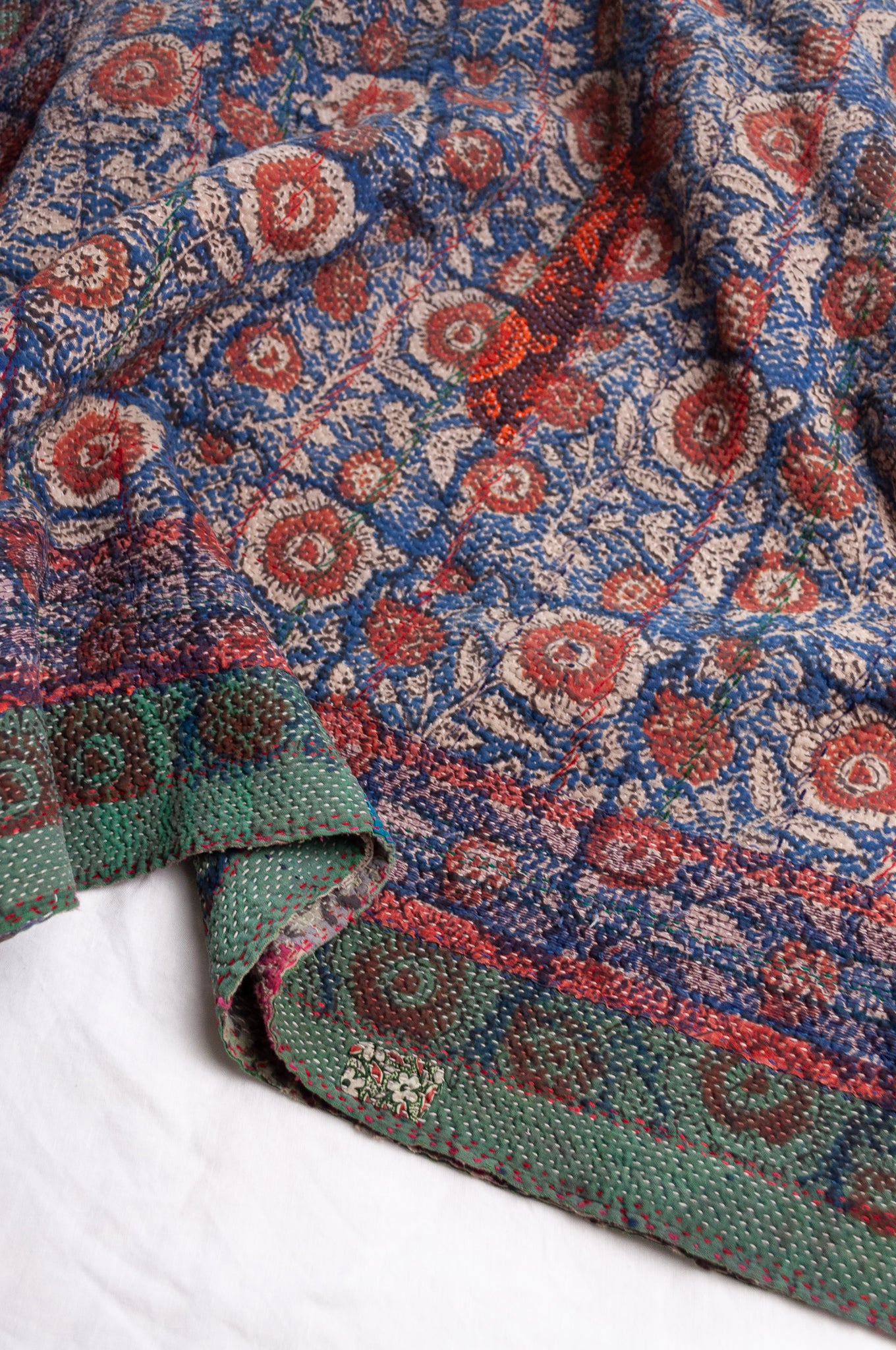 Bagru overdye blockprint vintage kantha quilt in red, ecru and denim blue with green borders.