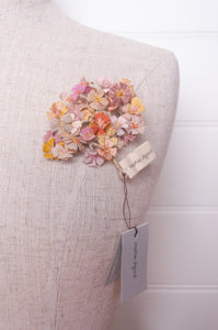 Sophie Digard crocheted flower brooch in warm neutral tones.