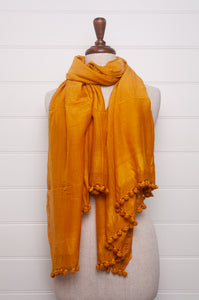 Silk and cotton scarf with pom poms in golden yellow.