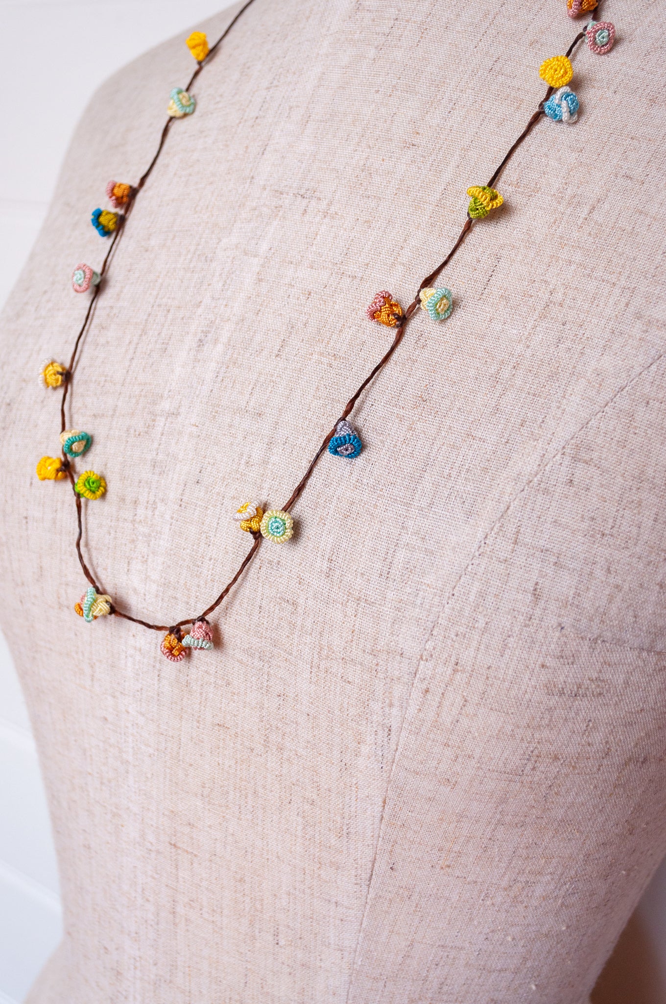 Handmade Moroccan button necklace in sky blue, soft yellow, rose pink and latte.