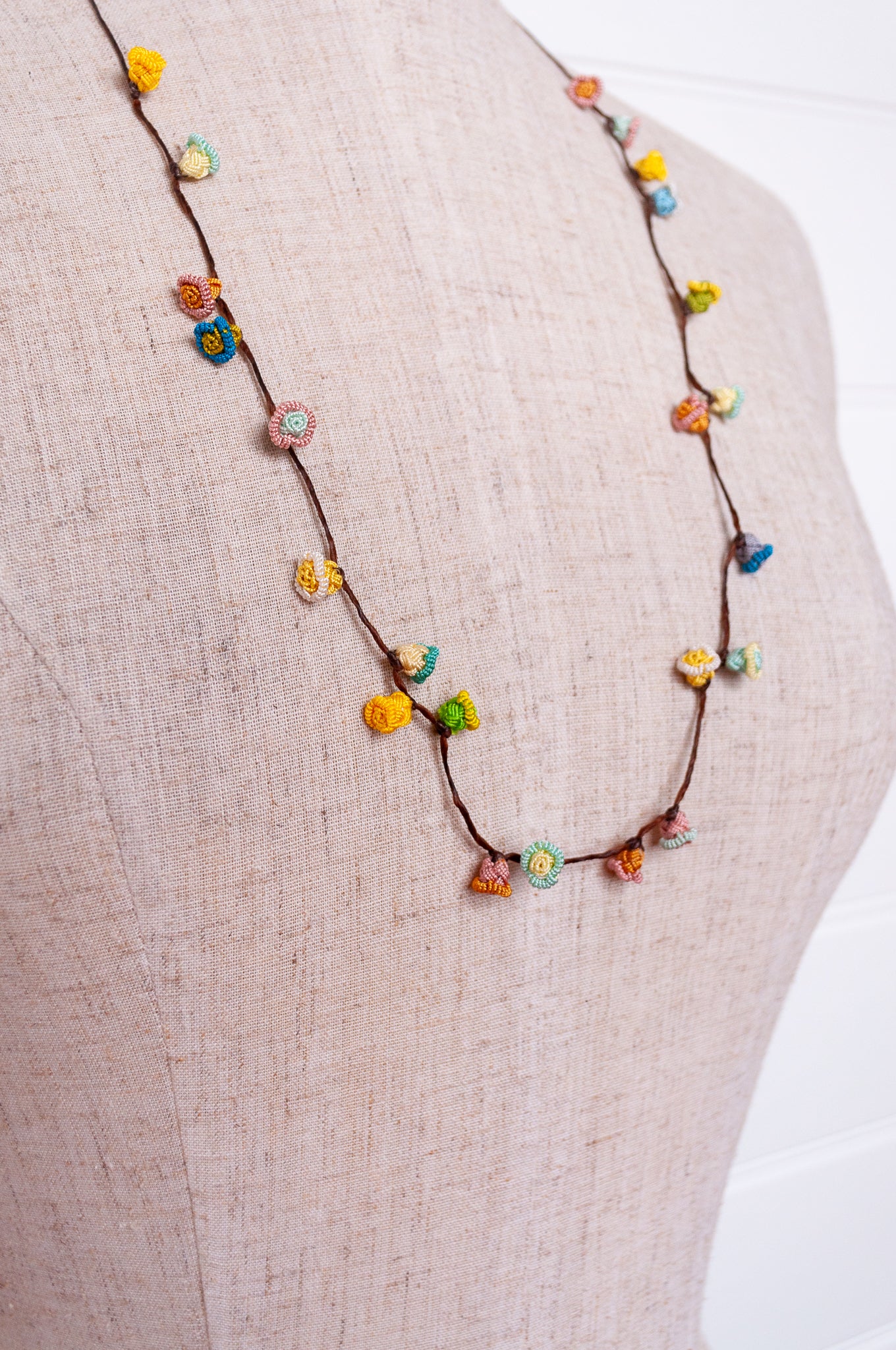 Handmade Moroccan button necklace in sky blue, soft yellow, rose pink and latte.