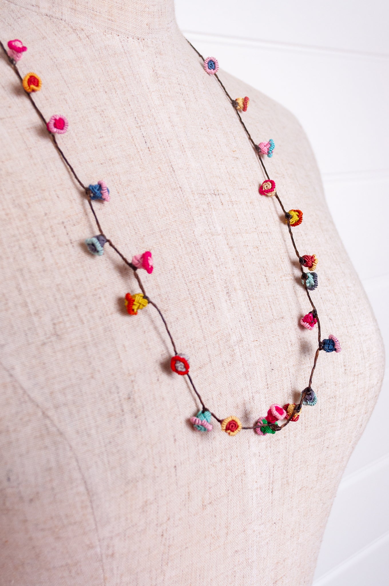 Handmade Moroccan button necklace in bright pastels blue, lemon yellow, rose pink.