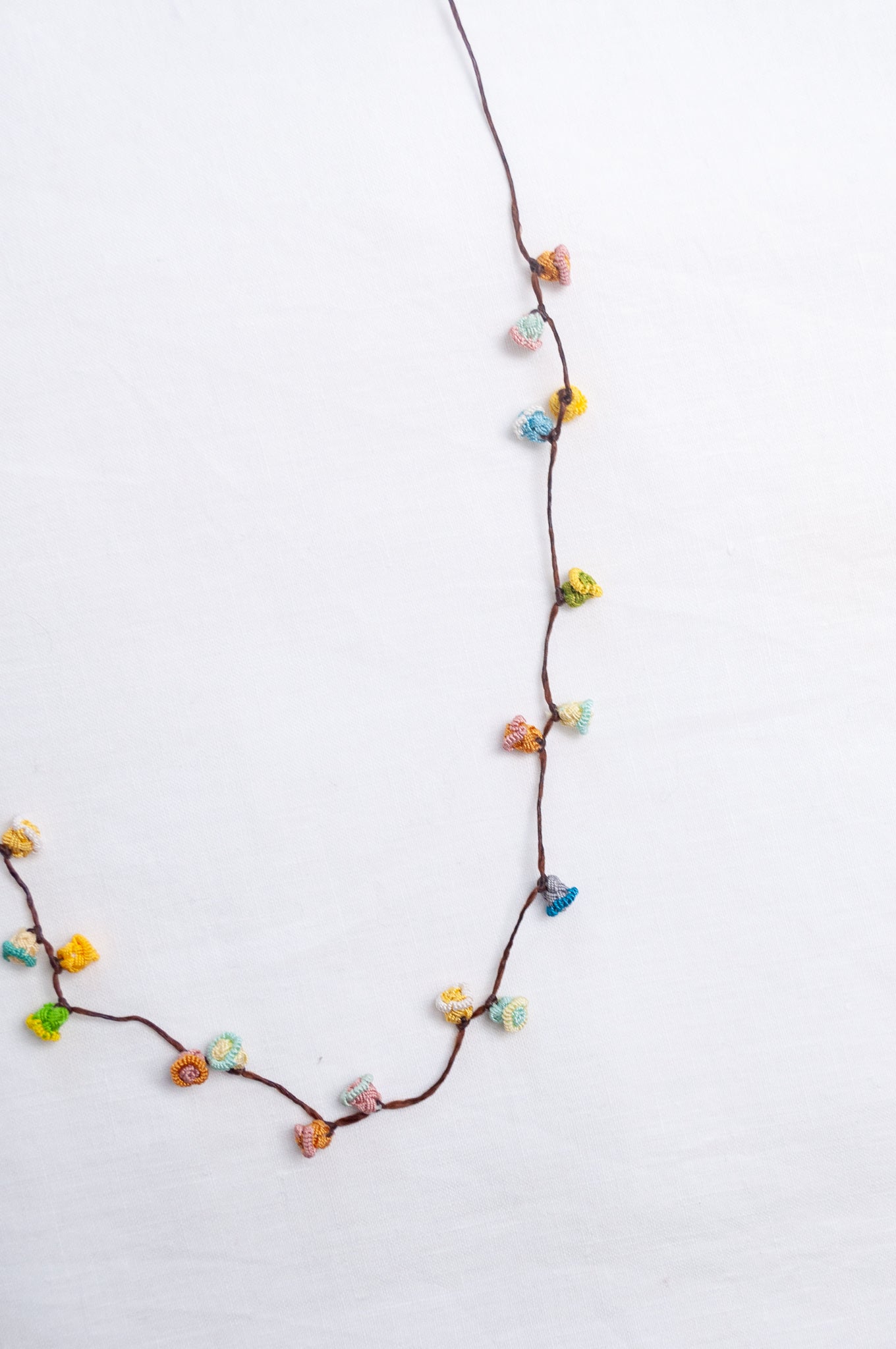 Handmade Moroccan button necklace in sky blue, soft yellow, rose pink and latte.
