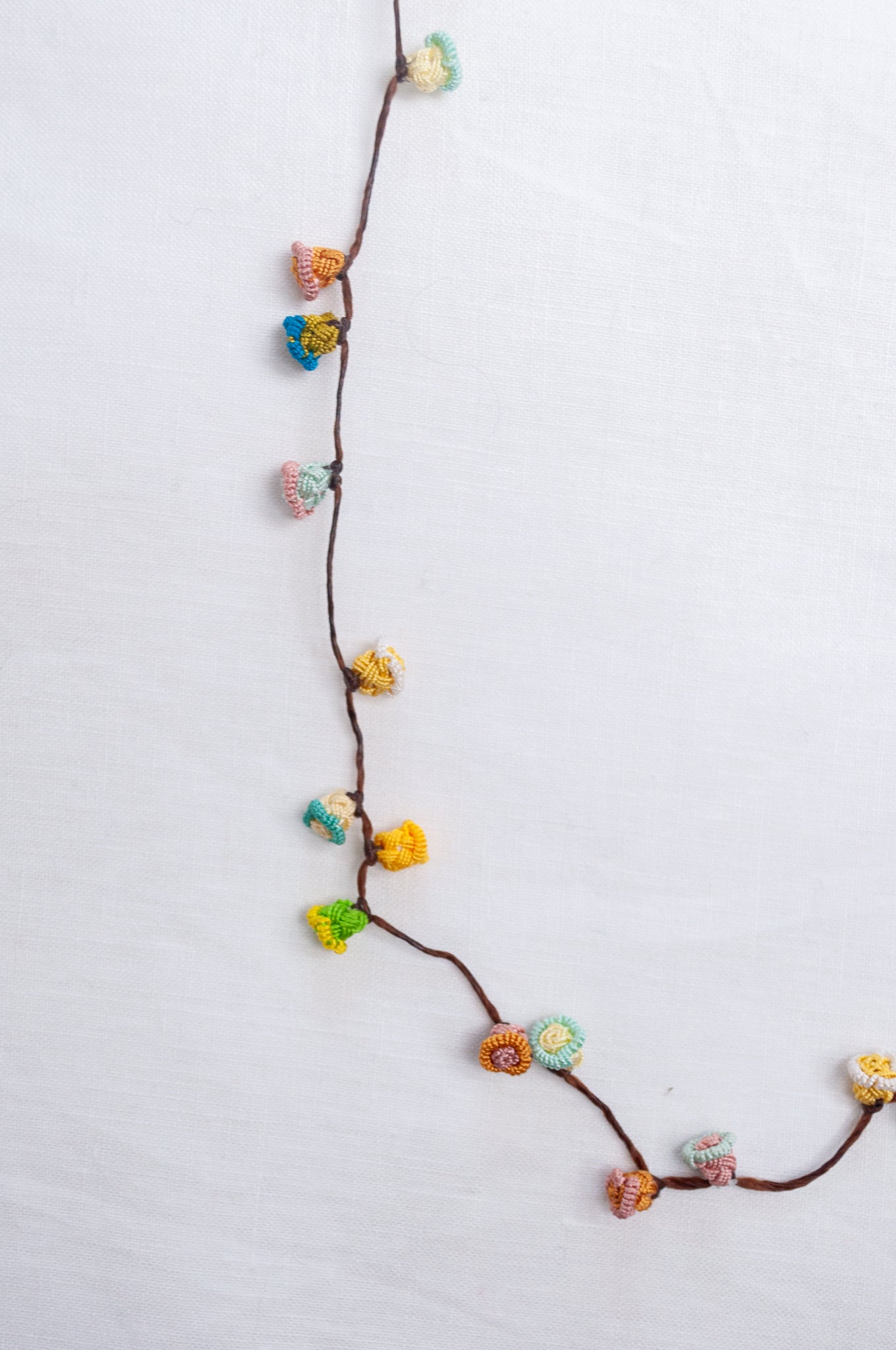 Handmade Moroccan button necklace in sky blue, soft yellow, rose pink and latte.