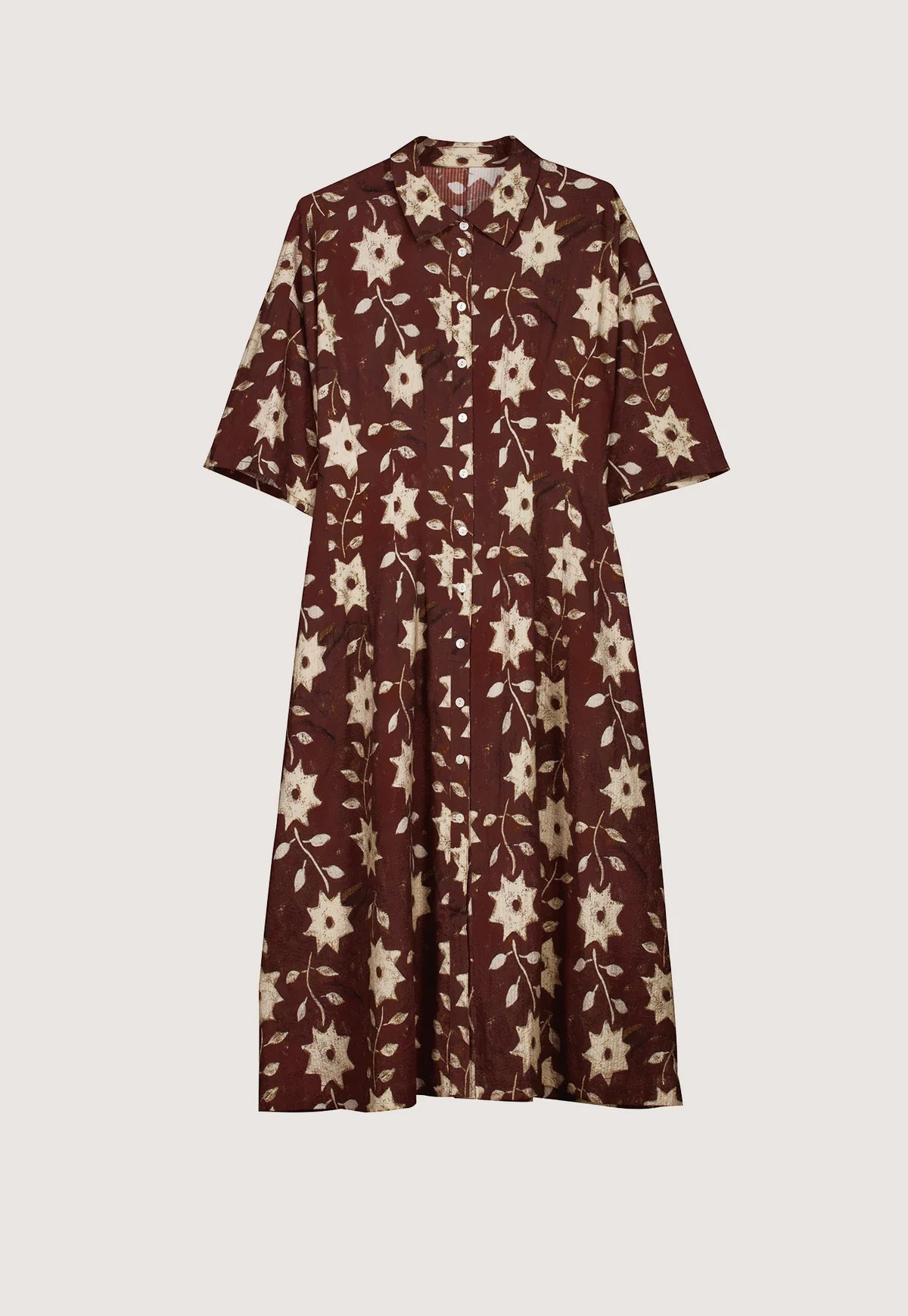 Nancybird Paloma short-sleeved button-front dress with an allover floral and starburst pattern in cream on a dark reddish-brown background.