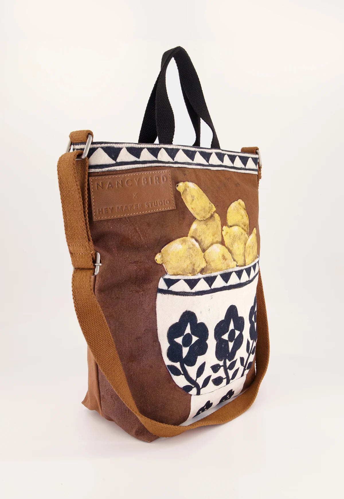 Nancybird brown shoulder bag featuring a front pocket printed with yellow lemons and a white floral pattern, set against a clean white background.
