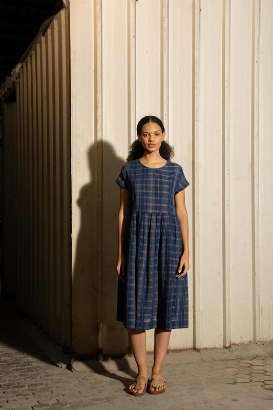 DVE Rayna dress in handloom indigo check cotton with subtle lurex stripe, cap sleeves and gathered skirt with side pockets.