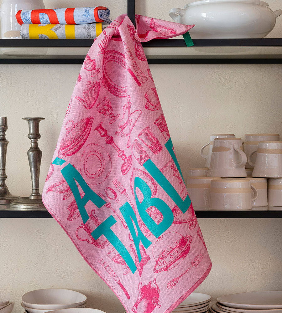 Le Jacquard Francais pure cotton jacquard weave made in France tea towel A Table pink with blue text.