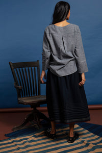 DVE Collection Jiana skirt in soft boiled wool, charcoal black with selvedge detailing, horizontal pleats and side pockets.