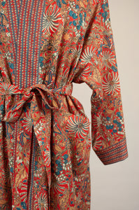 Cotton voile kimono robe dressing gown in a rust red palm print with red and blue matching geometric trim, close up showing pockets.