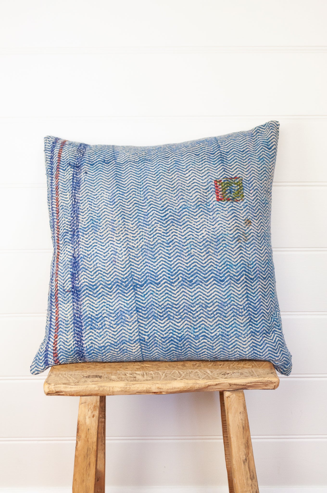 Vintage kantha quilt cushion, overdyed with blue and white blockprint chevron stripe pattern with red highlights.
