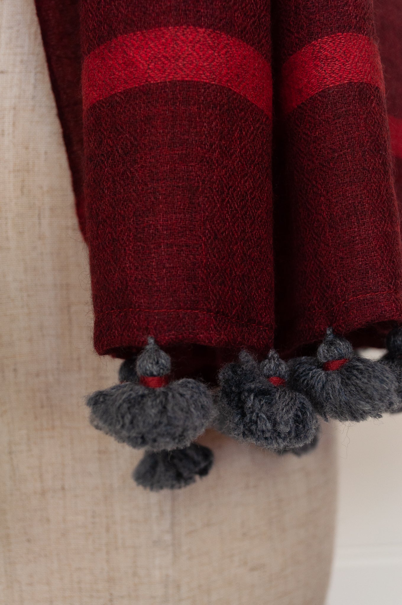 Juniper Hearth woven merino wool scarf, lightweight and very soft, melange dye from charcoal to cherry red, with handmade pompoms.