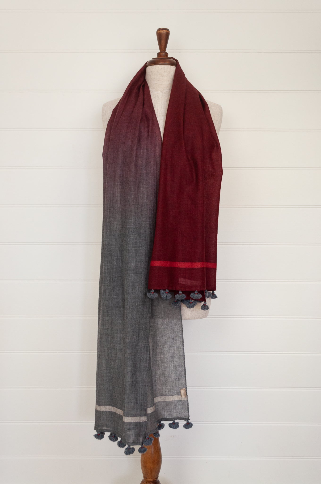 Juniper Hearth woven merino wool scarf, lightweight and very soft, melange dye from charcoal to cherry red, with handmade pompoms.
